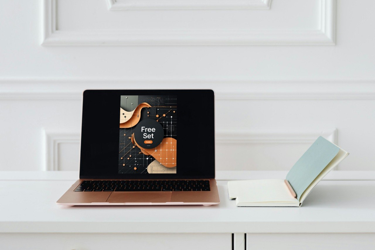 A laptop on a white desk displaying a digital cover for a 'Free Set' of guitar chord arrangements, styled with an open notebook on a white paneled wall background.